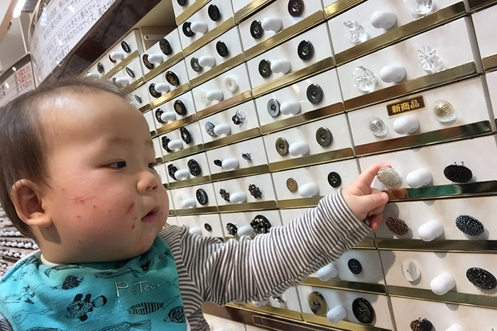 手芸店のボタンコーナーで、ボタンを触る赤ちゃん