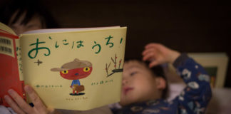 ママと一緒にベッドで絵本を読んでいる3歳の息子