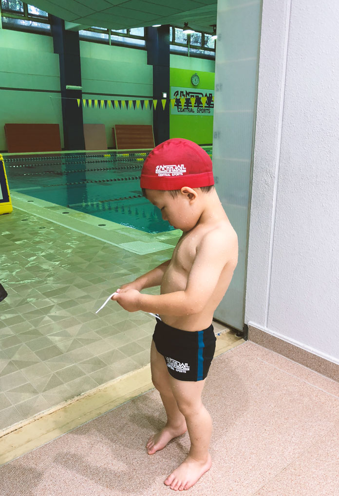 水着に着替えて、プールサイドでコーチを待つ4歳の息子