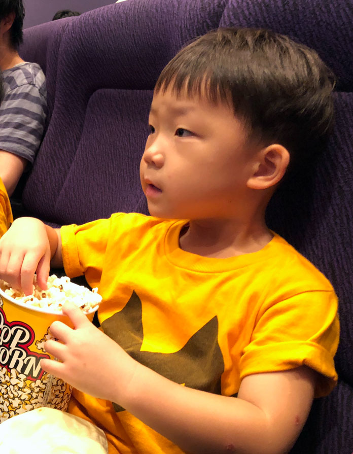 映画館の座席で、ポップコーンを食べる息子