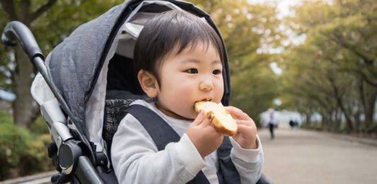 ベビーカーに乗っている赤ちゃんがパンを食べているところ