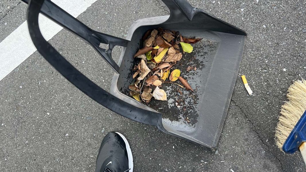 チリトリとホウキで、吸い殻や落ち葉を拾っている