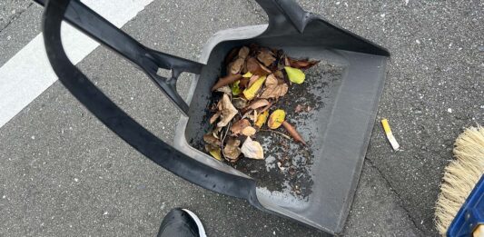 チリトリとホウキで、吸い殻や落ち葉を拾っている