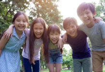 小学生5人組が笑顔で肩を組んでいる