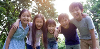 小学生5人組が笑顔で肩を組んでいる